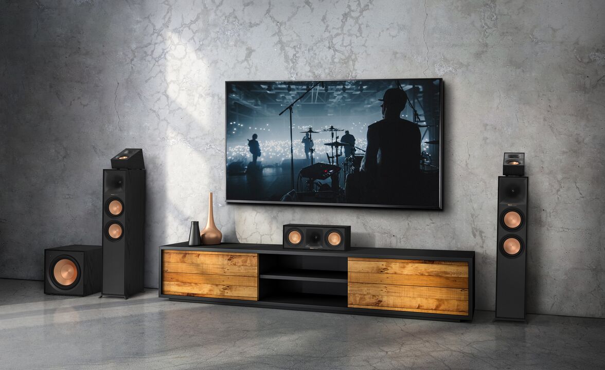 Bilde av Klipsch høyttalere i Reference II serien som står rundt og på en tv benk, under en TV
